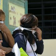 Women wear face masks as they wait to be assisted at a public clinic in Lima on April 14, 2015. | CRIS BOURONCLE/AFP via Getty Images